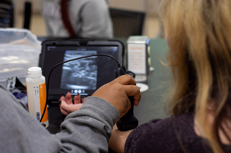 two people are viewed from behind looking at an ultrasound screen