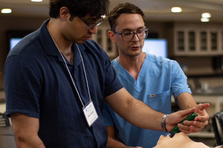 Two young men stare at an electronic device in a medical lab