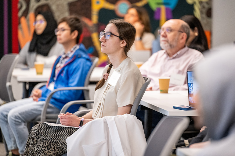 a group of seated audience members direct their attention to toward an unseen speaker