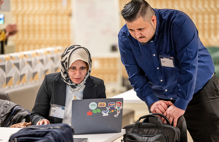 A woman and a man look at a laptop screen