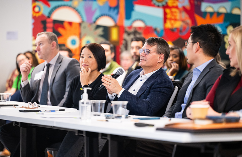 A panel of judges seated at a long table ask questions of competitors