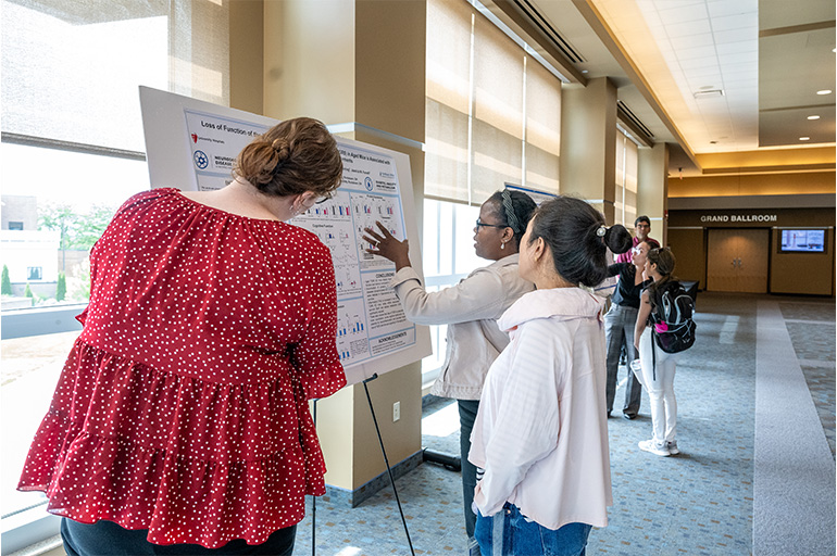 three women examine an academic poster