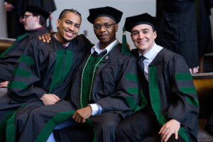 Three young men in academic regalia at commencement to receive their M.D. degrees