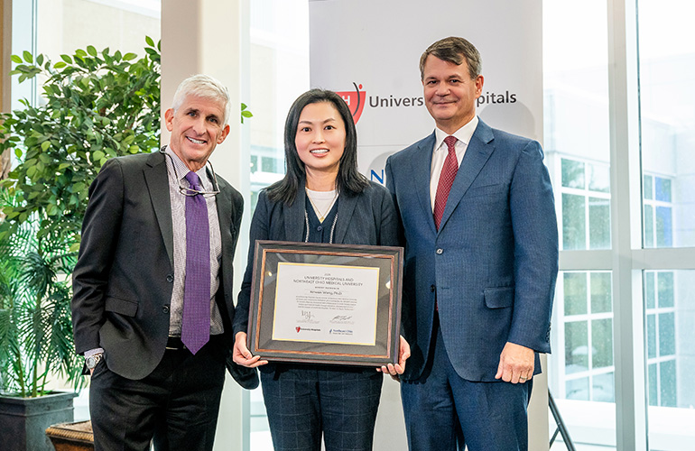 Dr. Xinwen Wang poses with her scholars certificate while Dr. Dan Simon and Dr. John T. Langell look on