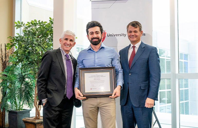 Ph.D. student Mirjavid Aghayev poses with his scholar certificate while Dr. Dan Simon and  Dr. John T. Langell look on