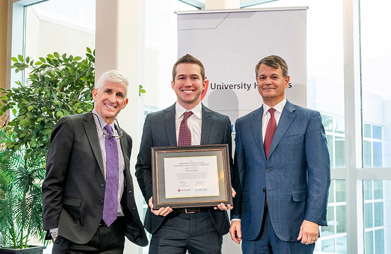Medical student Zachary Oatley poses with his scholar certificae while Dr. Dan Simon and Dr. John T. Langell look on