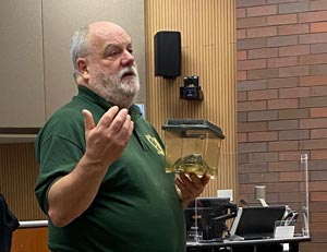 A man makes a point while talking before a class.