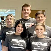 Certified Anesthesiologist Assistant students in matching t-shirts stand in a group, smiling.