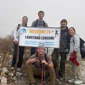 NEOMED students hiking a trail in Nepal hold a sign that shows their elevation.