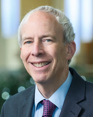 A medical school dean wearing a red tie and a gray jacket.