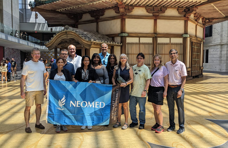 A group of people hold a banner that reads: NEOMED