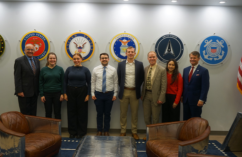 A group of people pose in front of military seals