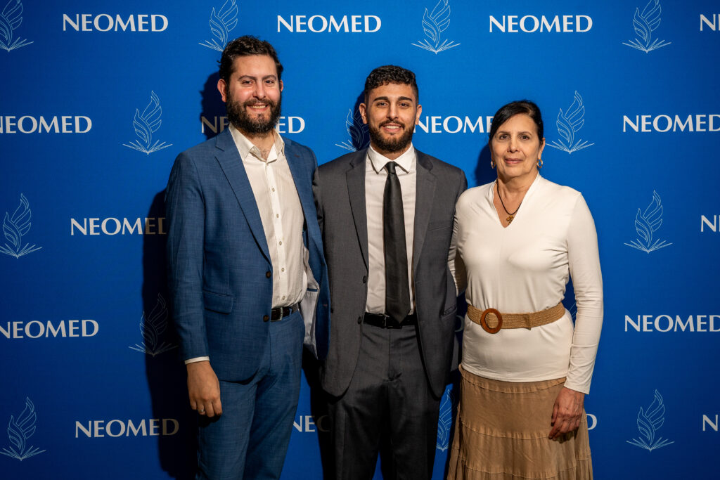 Members of the Tiliakos family pose in front of a NEOMED backdrop