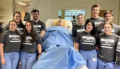 Anesthesiologist assistant students stand in a group photo in an operating room.