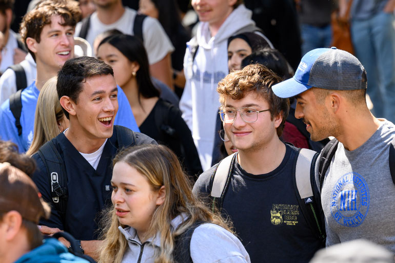 A group of students talk while walking on campus.
