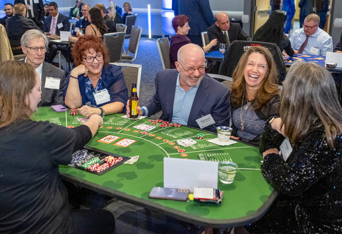 A group of poker players laugh while sitting around a table.