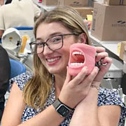 A woman holding a set of fake teeth.