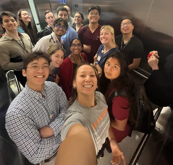 A group photo of students in an elevator, all smiling.