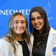 Two smiling pharmacy students in white coats.