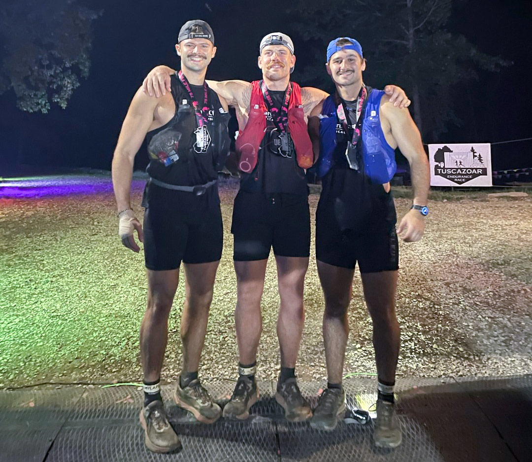The three NEOMED runners after the race, standing shoulder to shoulder in the dark.