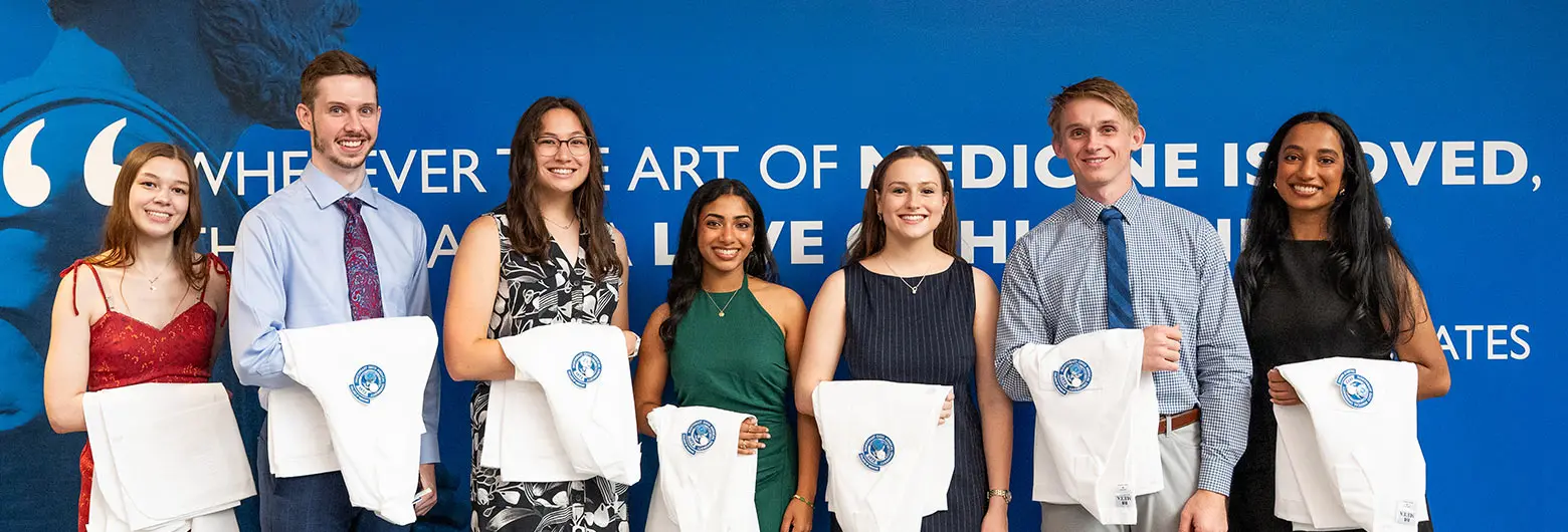 Seven students hold their white coats prior to the ceremony.