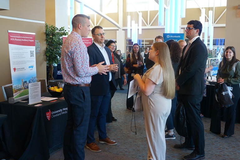 Group of people talk at the UH tabel at the 2025 Pharmacy Career Expo