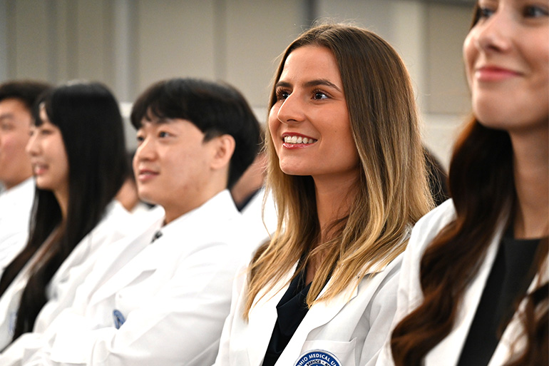 A line of students smile during an assembly