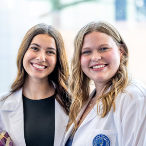Two smiling students in white coats.
