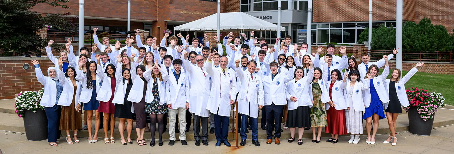 Members of the incoming 2026 class stand outside of NEOMED wearing their white coats for a group photo.