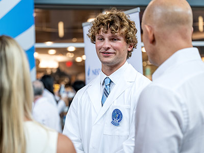 A smiling dentistry student talks with his parents after the white coat ceremony.