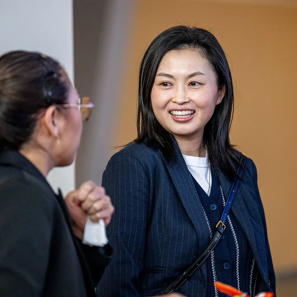 A faculty member chats with a student during a campus event.
