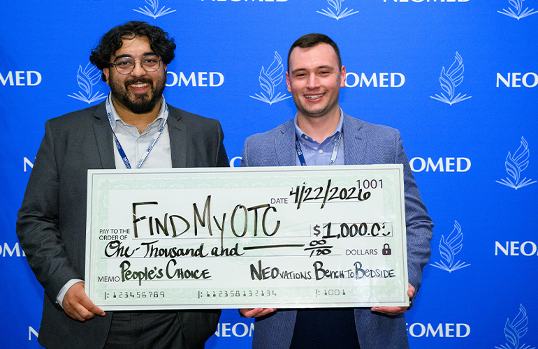Two people hold an oversized check.