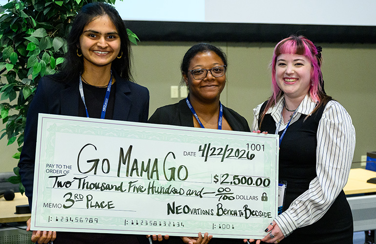 Three people stand holding an oversized check.
