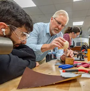 A faculty member guides students assembling a project with tools and electronic components in a makers space at NEOMED.
