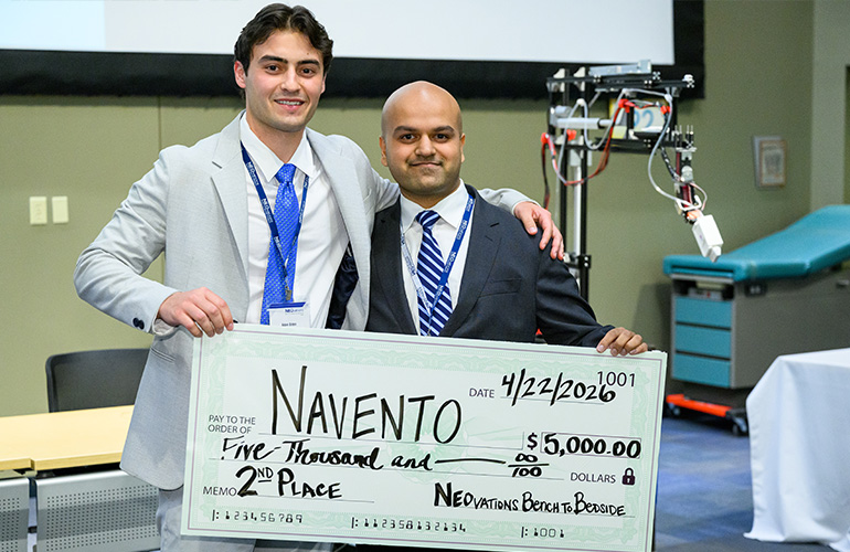 Two people stand holding an oversized check.