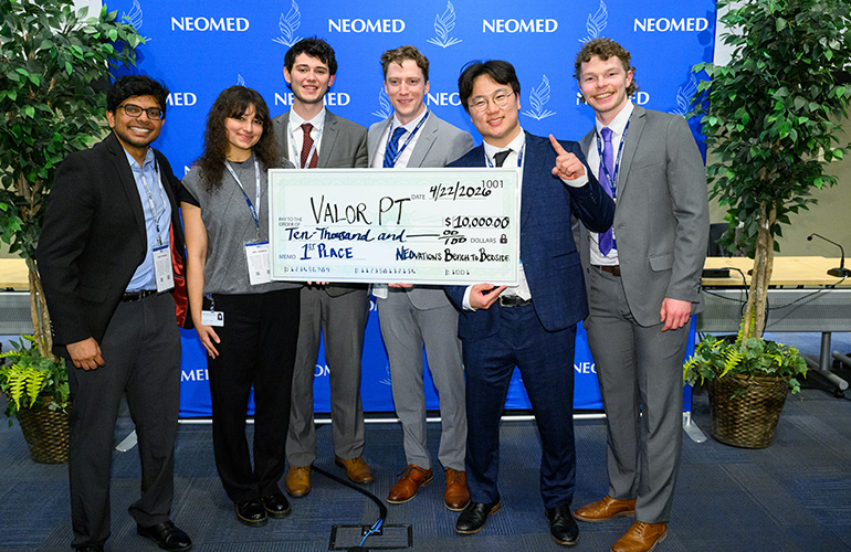 A group of people stand holding an oversized check.