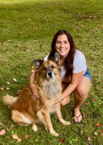 A woman smiles while posing with her dog