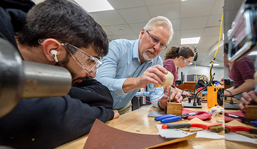A faculty member guides students assembling a project with tools and electronic components in a makers space at NEOMED.