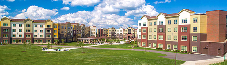 The Village at NEOMED with a large grassy common area in the foreground.