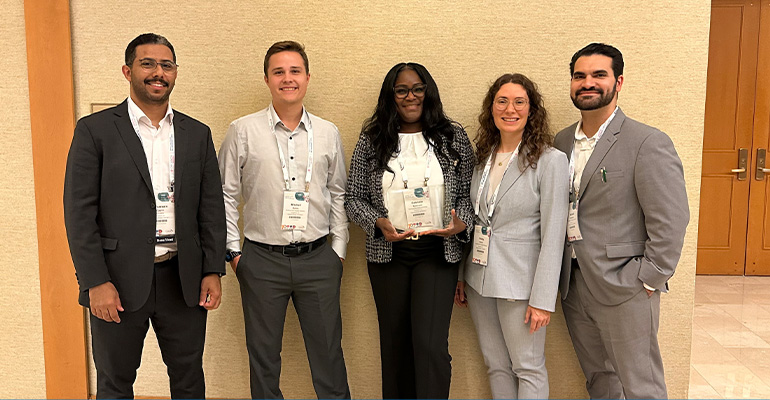 A young woman holds a crystal award in the center of a group of conference attendees