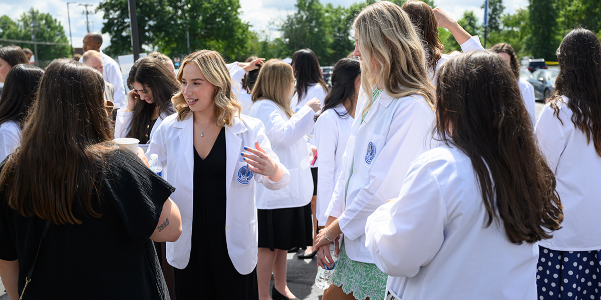A group of young women in white coats chat outside