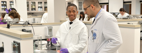 Young man compounding medication in a pharmacy lab