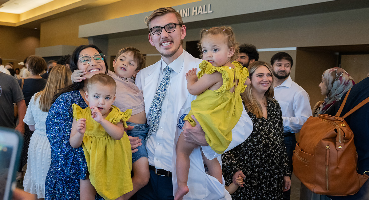 Man in white coat surrounded by his family