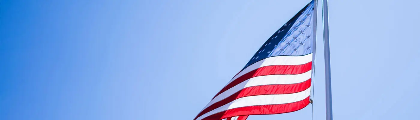 The American flag with a blue sky behind it.