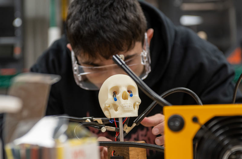 A student wearing protective eyeware works on a prototype in a NEOMED lab.