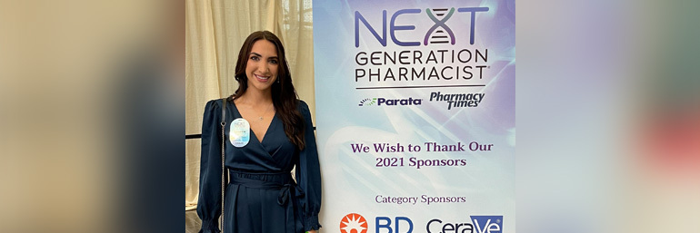 Raneem (Alayoubi) Pallotta stands next to a sign that says "Next Generation Pharmacist."