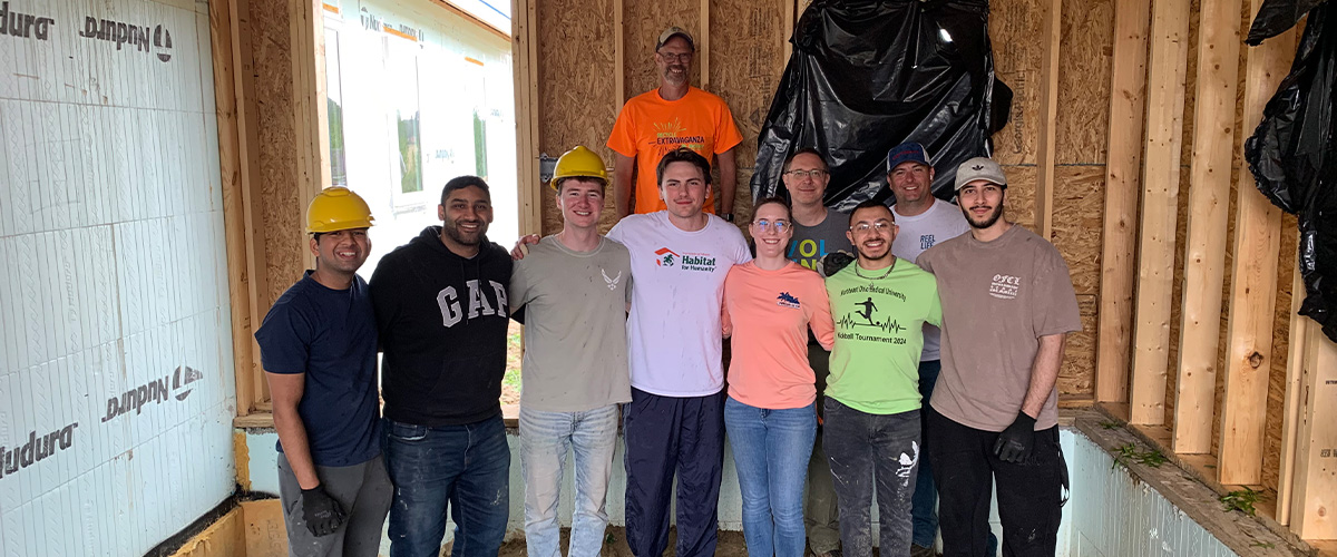 Group of people pose inside a construction site.