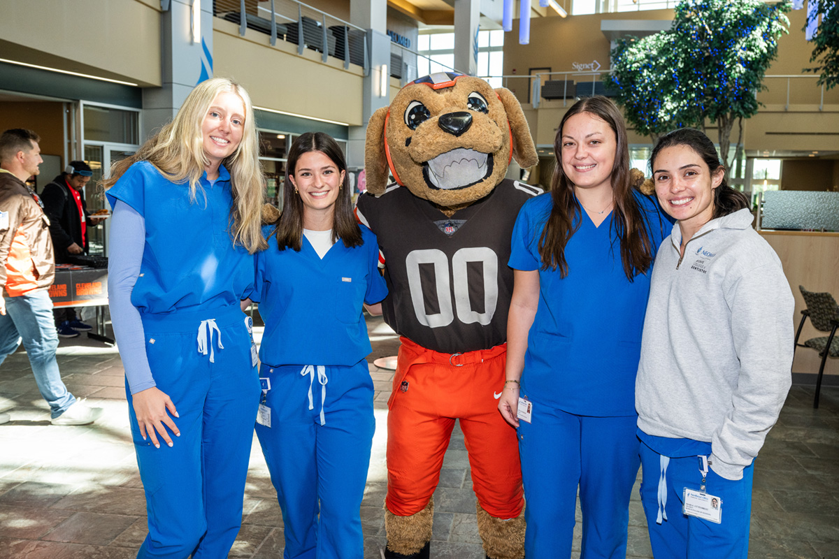 Four female NEOMED students standing with Cleveland Browns mascot dog smiling inside NEOMED