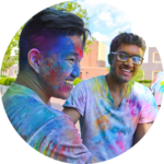 Two students in colorful t-shirts laughing during a campus event.