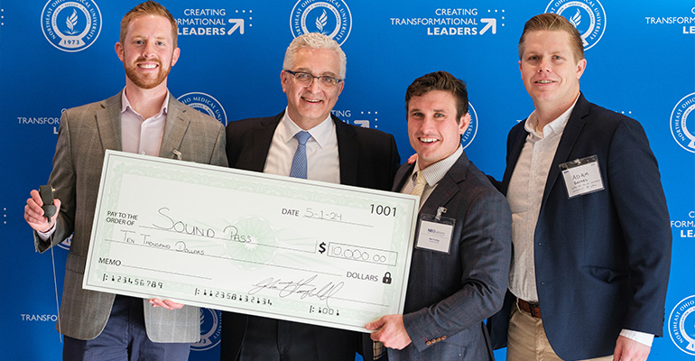 Four men holding an oversized check